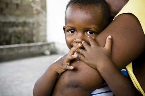 Liten afrikansk gutt holder rundt armen til sin mor